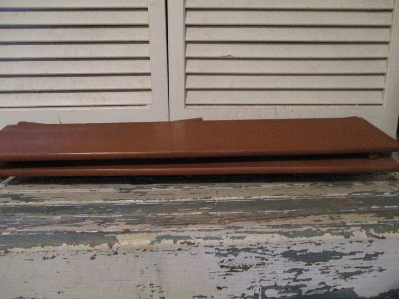 May include: Two brown leather-like rectangular pieces stacked on top of each other. The pieces are smooth and have a slight sheen.