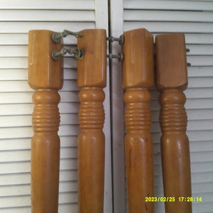 May include: Four wooden table legs with metal brackets. The legs are a light brown color and have a fluted design.