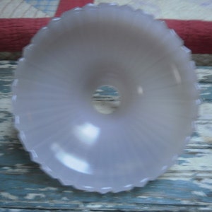May include: A white frosted glass lampshade with a scalloped edge and a central hole for a light bulb.