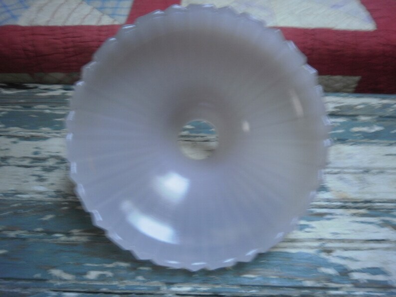 May include: A white frosted glass lampshade with a scalloped edge and a central hole for a light bulb.