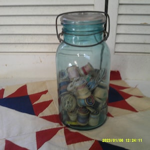 Beautiful Blue/Aqua Ball Ideal Canning Jar with Clear Lid and bailing wire. Filled with Wood Spools of thread and sewing notions.