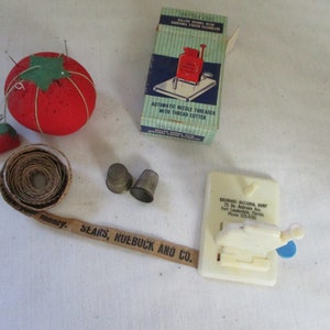 What a Collection. Vintage Red Tomato Pin Cushion,  2 Brass Thimbles, Vintage Paper Measuring tape, and Automatic Needle Threader.