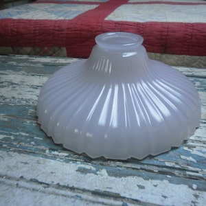 May include: A white frosted glass lampshade with a fluted design. The lampshade is round and has a wide opening at the top.