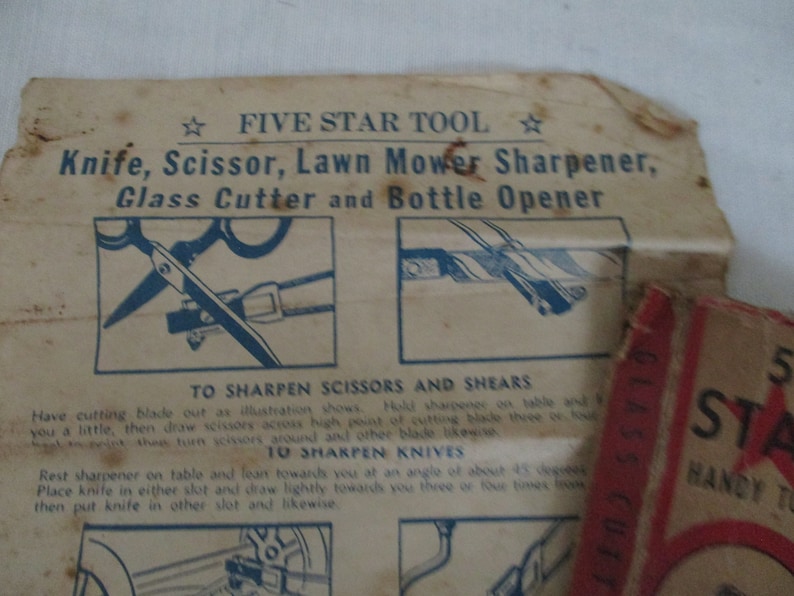 May include: Close-up of a vintage Five Star Tool sharpener with instructions on how to sharpen scissors, shears, knives, and lawn mower blades. The tool is made of metal and has a blue and white design.