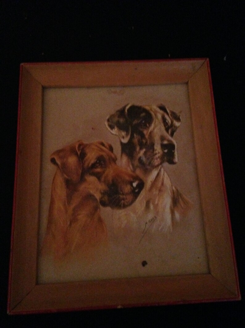 May include: A framed print depicting two dogs, one with reddish-brown fur and the other with a mix of brown and white. The artwork is set within a wooden frame with a red inner edge, creating a classic aesthetic.