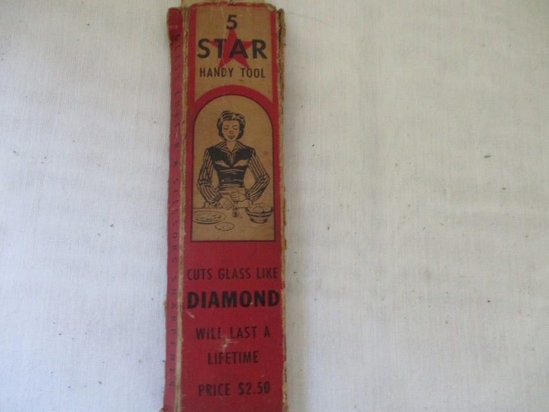 May include: Red and white cardboard box with a red star and the text "5 STAR HANDY TOOL". The box also has a black and white illustration of a woman using a tool to cut glass. The text "CUTS GLASS LIKE DIAMOND" is printed on the box, along with "WILL LAST A LIFETIME" and "PRICE $2.50".