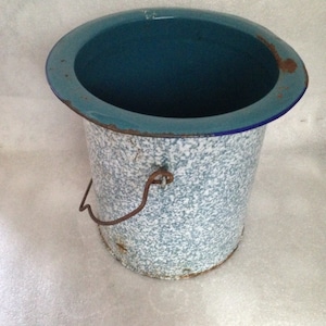 Może przedstawiać: Biały emaliowany kubeł z niebieskim rantem i wzorzystym wzorem. Kubeł ma metalowy uchwyt i jest pusty.