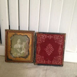 May include: Two antique picture frames, one with a gold frame and a black mount, the other with a black frame and a red velvet mount.