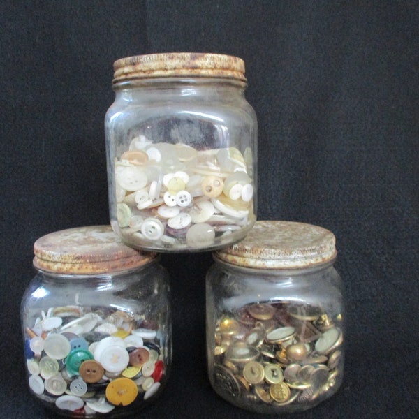 Three Vintage Duraglas Jar, Rusty Lids, Button Collections, white Mother of Pearl buttons, Gold and Brass Jar, and Assorted Colored Buttons.