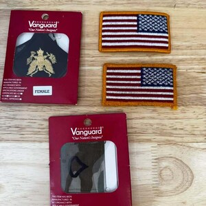 May include: Two rectangular embroidered American flag patches with gold borders and two Vanguard brand packaging cards. One card displays a gold eagle insignia on black fabric, and the other shows a dark green chevron patch.