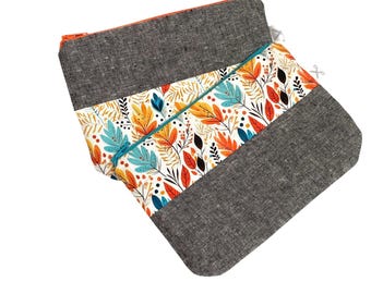 Könnte beinhalten: Ein Set aus drei grauen und weißen Reißverschlusstaschen mit einem bunten Blumenmuster. Die Taschen sind aus Leinenstoff gefertigt und haben einen kontrastierenden orangefarbenen Reißverschluss.