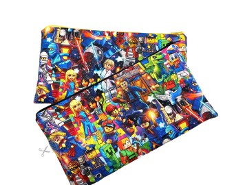 May include: A black zippered pouch with a colorful print of various Lego minifigures, including superheroes, astronauts, and other characters. The print is on a black background with yellow accents.