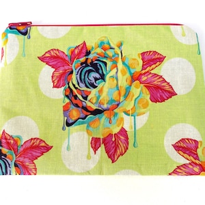May include: A green zippered pouch with a white polka dot pattern and a colorful dripping rose design. The rose is made up of pink, yellow, blue, and green colors.