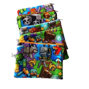 May include: A stack of six colorful zippered pouches with a Minecraft theme. The pouches feature various characters from the game, including Steve, Creeper, and a zombie. The pouches are made of a soft, durable fabric and are perfect for storing small items.