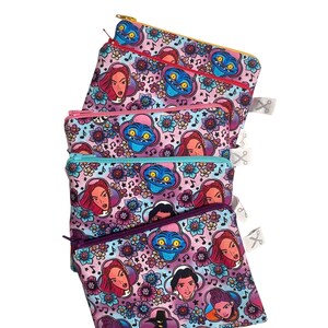 Könnte beinhalten: Vier Reißverschlusstaschen mit einem farbenfrohen Muster mit Zeichentrickfiguren und floralen Designs. Die Taschen haben unterschiedlich farbige Reißverschlüsse, darunter Gelb, Rosa und Blau. Der Hintergrund ist weiß.