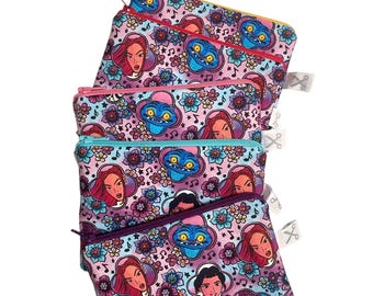 Könnte beinhalten: Vier Reißverschlusstaschen mit einem farbenfrohen Muster mit Zeichentrickfiguren und floralen Designs. Die Taschen haben unterschiedlich farbige Reißverschlüsse, darunter Gelb, Rosa und Blau. Der Hintergrund ist weiß.