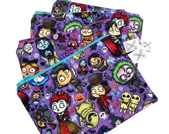 Könnte beinhalten: Ein Set aus vier violetten Reißverschlusstaschen mit einem bunten Druck verschiedener Figuren aus beliebten Halloween-Filmen. Der Druck enthält Figuren wie Jack Skellington, Sally und Oogie Boogie.