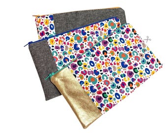Könnte beinhalten: Drei Reißverschlusstaschen in verschiedenen Größen und Designs. Eine Tasche ist goldfarben, eine andere hat ein buntes Leopardenmuster und die dritte ist aus dunkelgrauem Stoff. Alle haben einen Reißverschluss.