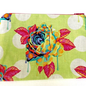 May include: A green zippered pouch with a white polka dot pattern and a colorful dripping rose design.