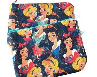 Könnte beinhalten: Zwei Reißverschlusstaschen mit einem sich wiederholenden Muster von Cartoon-Prinzessinnen in verschiedenen Kleidern und Frisuren. Der Hintergrund ist dunkelblau mit einem verwitterten, Vintage-Look. Eine Tasche hat einen roten Reißverschluss, die andere einen türkisfarbenen Reißverschluss.