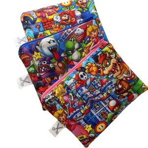 Puede incluir: Cuatro bolsas con cremallera de colores con una variedad de personajes de Super Mario impresos en ellas. Las bolsas están apiladas una encima de la otra.