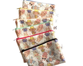 Könnte beinhalten: Sechs rechteckige Reißverschlusstaschen mit einem sich wiederholenden Cartoon-Charaktermuster. Die Taschen haben unterschiedlich farbige Reißverschlüsse, darunter blau, gelb, grün, rot und schwarz. Die Taschen sind übereinander gestapelt.