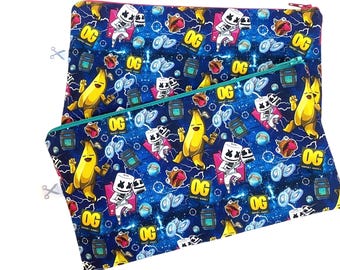 Könnte beinhalten: Zwei blaue Reißverschlusstaschen mit einem sich wiederholenden Muster aus einer Cartoon-Marshmallow-Figur, Bananen und dem Wort "OG". Die Taschen haben einen türkisfarbenen Reißverschluss und einen weißen Hintergrund.