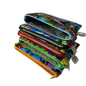 May include: A stack of six colorful zippered pouches with different patterns. The pouches are made of fabric and have a mesh lining. The top pouch has a Minecraft-themed pattern.