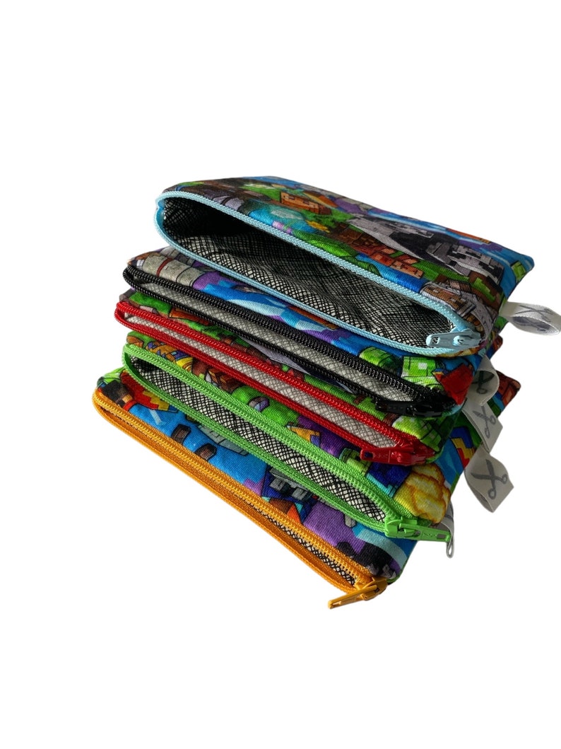 May include: A stack of six colorful zippered pouches with different patterns. The pouches are made of fabric and have a mesh lining. The top pouch has a Minecraft-themed pattern.
