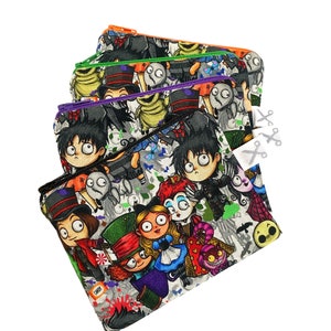 Puede incluir: Un conjunto de cuatro bolsas con cremallera de colores con un fondo blanco y un patrón repetido de personajes de dibujos animados de películas populares de Halloween. Los personajes incluyen a Jack Skellington, Sally, Oogie Boogie y otros.