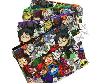 May include: A set of four colorful zippered pouches with a white background and a repeating pattern of cartoon characters from popular Halloween movies. The characters include Jack Skellington, Sally, Oogie Boogie, and others.