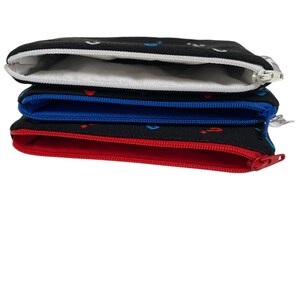 Puede incluir: Cuatro bolsas negras con cremallera y forros de diferentes colores. Las bolsas est&aacute;n apiladas una encima de la otra. La bolsa superior tiene un forro blanco, la segunda bolsa tiene un forro azul, la tercera bolsa tiene un forro rojo y la bolsa inferior tiene un forro negro.