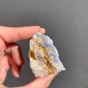 May include: A blue and white agate crystal with brown inclusions. The crystal is rough and has a natural shape.