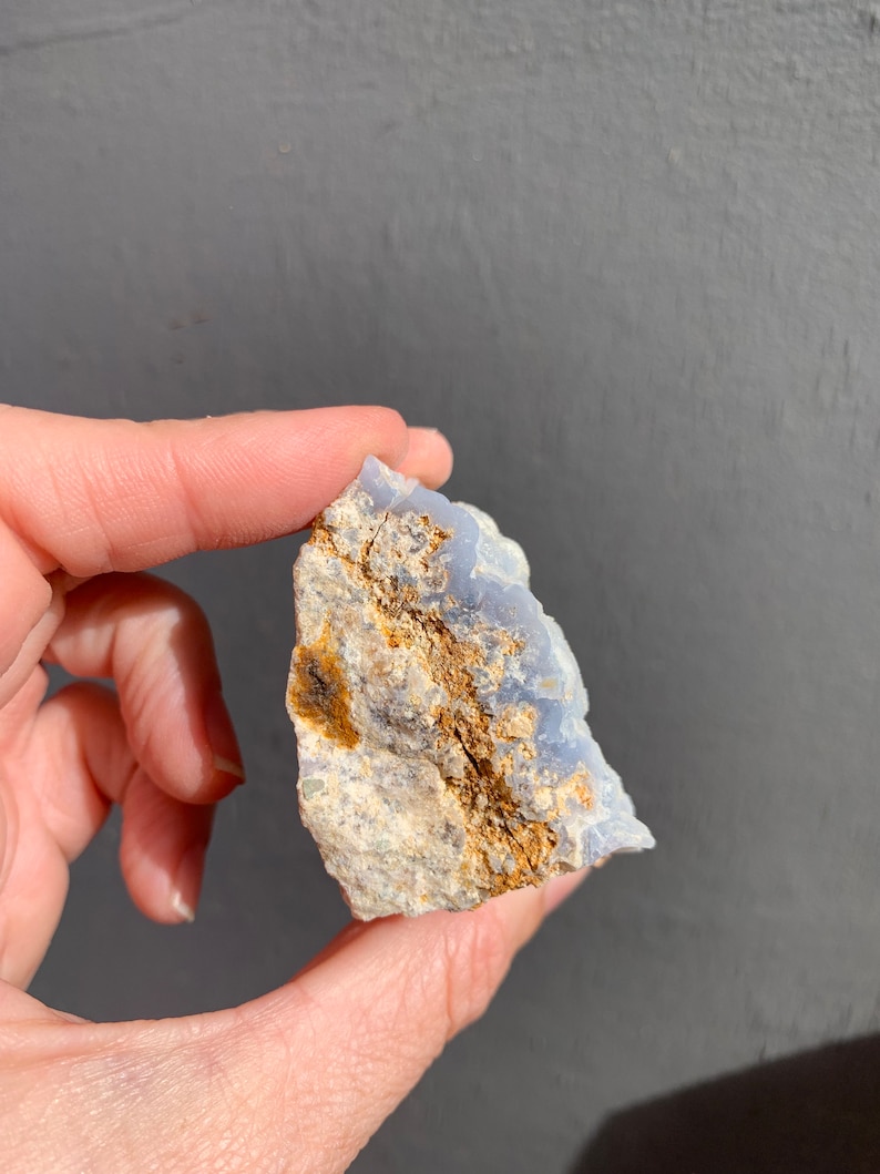 May include: A blue and white agate crystal with brown inclusions. The crystal is rough and has a natural shape.