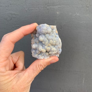 May include: A cluster of blue chalcedony with a bubbly texture. The chalcedony is a light blue color with a white, milky appearance.