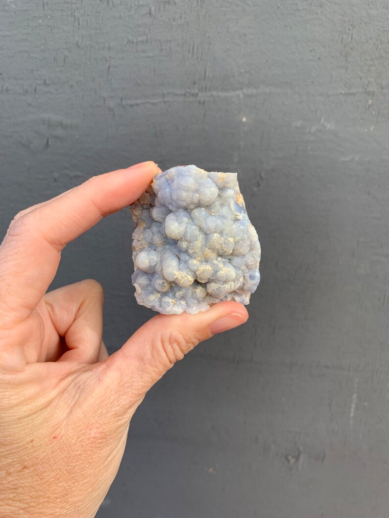 May include: A cluster of blue chalcedony with a bubbly texture. The chalcedony is a light blue color with a white, milky appearance.