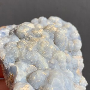 May include: A cluster of blue chalcedony with a white, sparkly, crystalline texture. The chalcedony has a rough, natural surface.