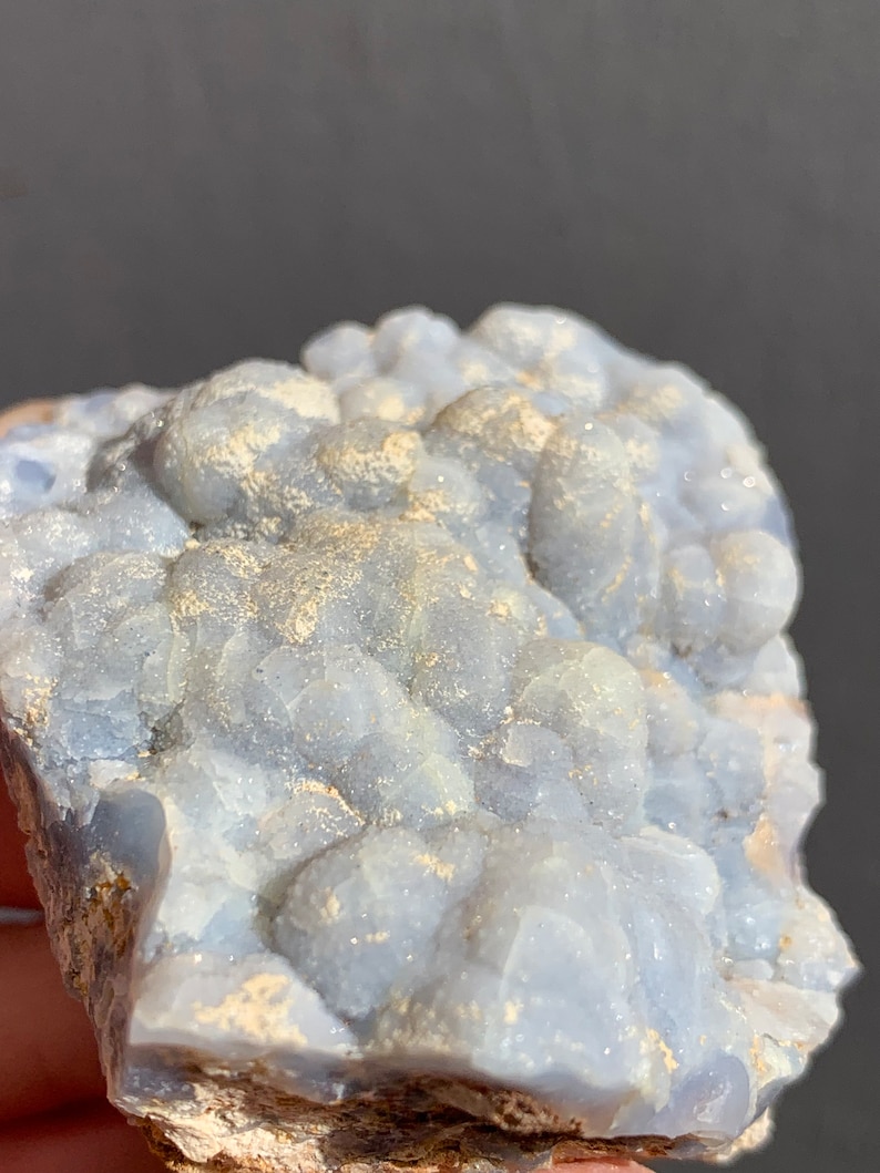 May include: A cluster of blue chalcedony with a white, sparkly, crystalline texture. The chalcedony has a rough, natural surface.