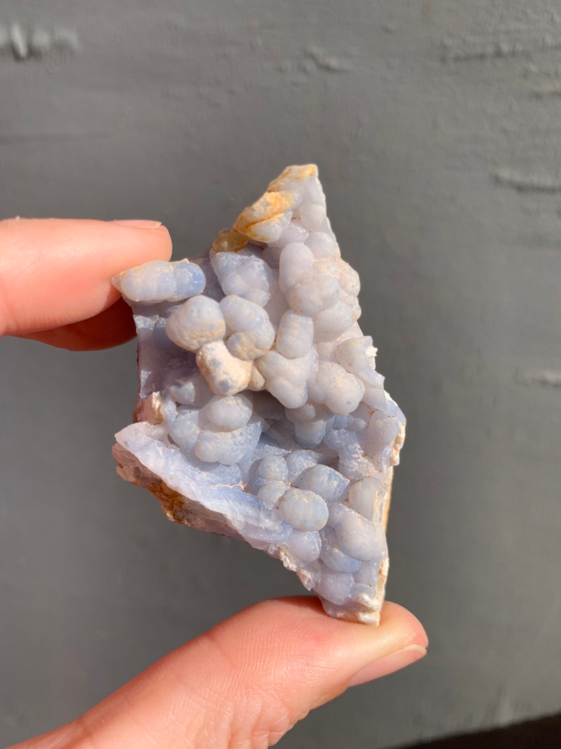 May include: A blue and white agate geode with a cluster of small, round, white crystals. The geode is a natural formation and has a rough, irregular shape.