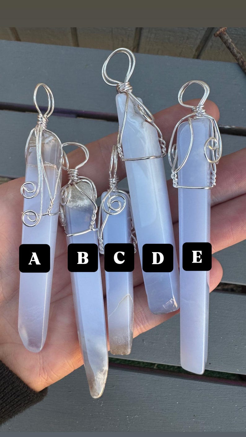 Pu&ograve; includere: Cinque ciondoli in cristallo di agata blu avvolti in filo d'argento. I ciondoli sono etichettati dalla A alla E.