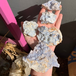May include: Four blue and white agate crystal clusters with a rough, natural texture. The clusters are various sizes and shapes, with some having a more rounded form and others being more angular.