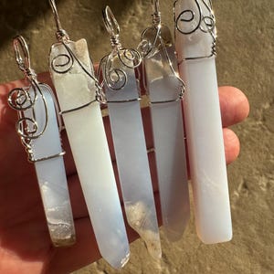 Pu&ograve; includere: Cinque ciondoli in cristallo di agata blu con filo d'argento avvolto intorno. I ciondoli sono di forme e dimensioni diverse, ma sono tutti molto belli.