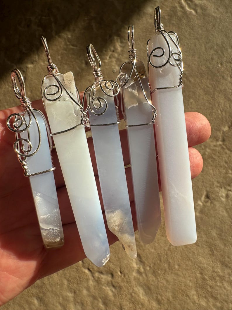 Pu&ograve; includere: Cinque ciondoli in cristallo di agata blu con filo d'argento avvolto intorno. I ciondoli sono di forme e dimensioni diverse, ma sono tutti molto belli.