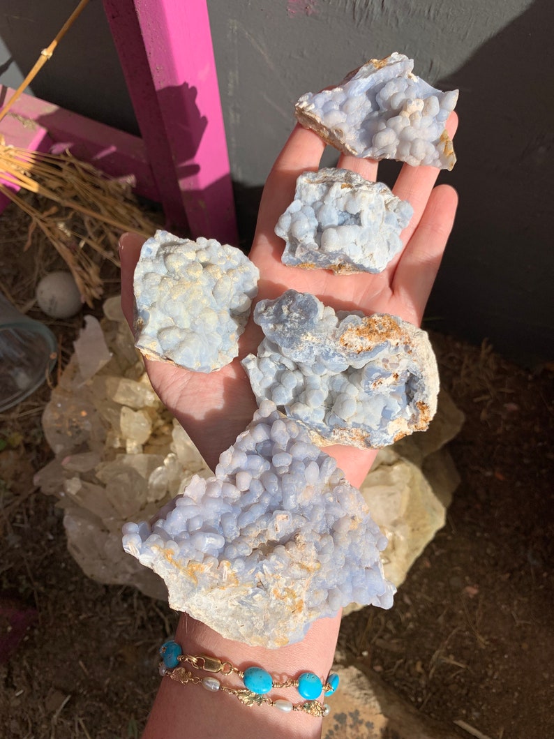 May include: A collection of four blue chalcedony nodules with a white and gray matrix. The nodules are clustered together and have a rough, textured surface.