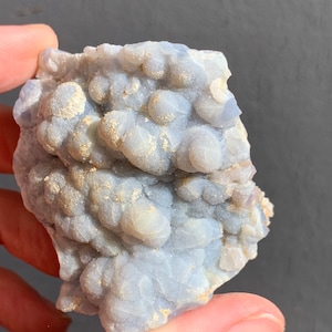 May include: A blue and white agate geode with a rough, textured surface. The geode is filled with small, white crystals.