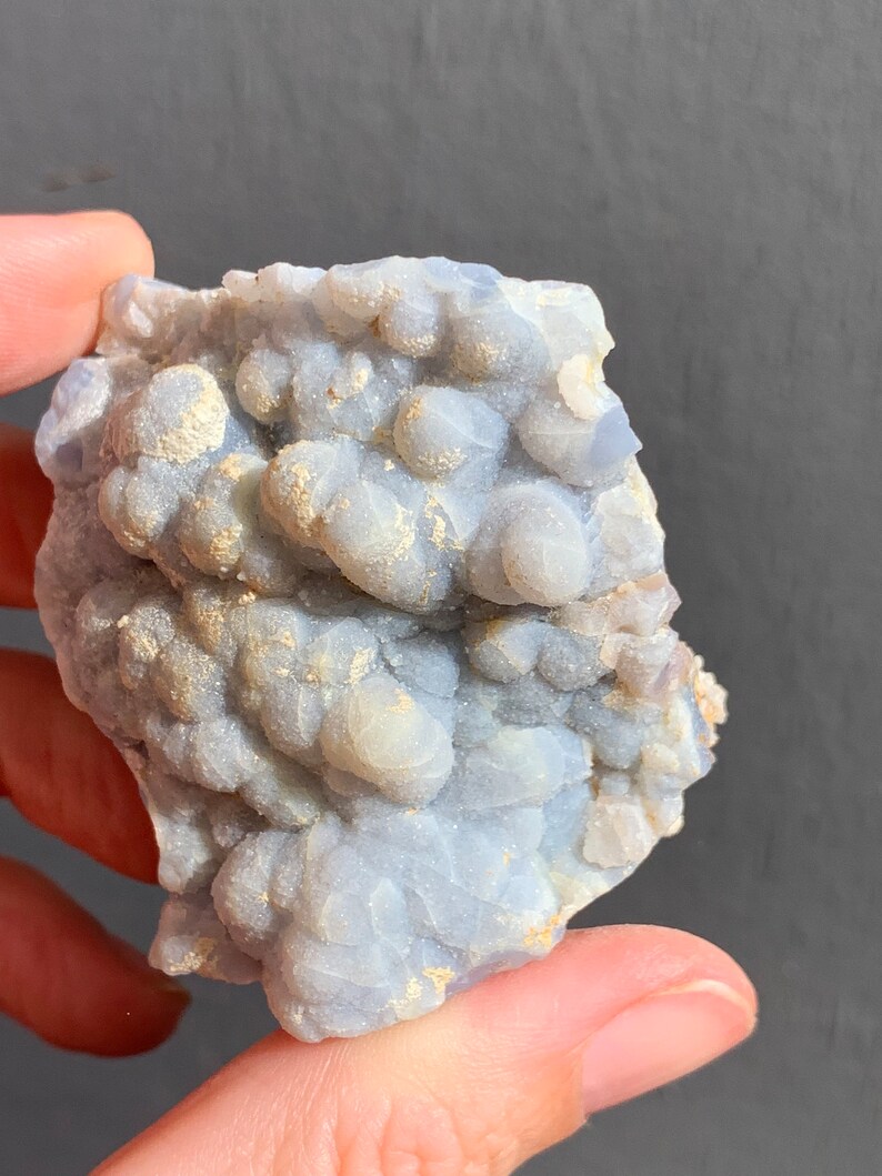 May include: A blue and white agate geode with a rough, textured surface. The geode is filled with small, white crystals.