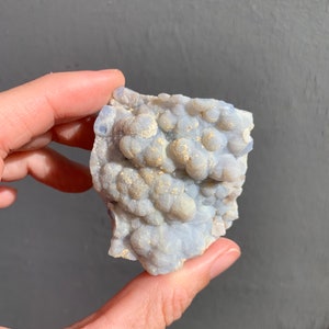 May include: A cluster of blue chalcedony with a bubbly texture and a light gray background.