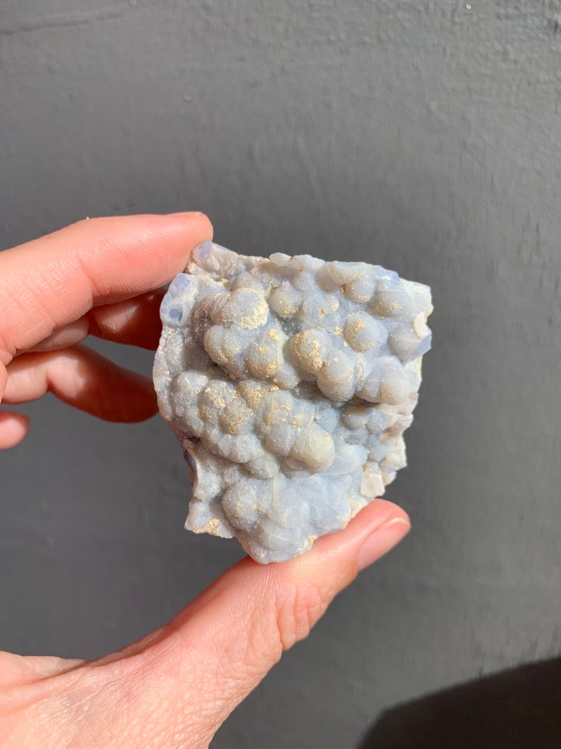 May include: A cluster of blue chalcedony with a bubbly texture and a light gray background.