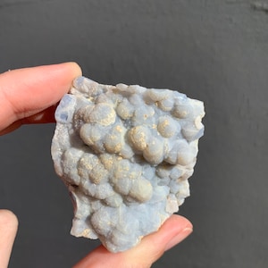 May include: A close-up of a light blue and white agate geode with a rough, textured surface. The geode is filled with small, round, white crystals.