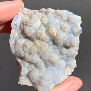 May include: A light blue and white agate geode with a rough, textured surface. The geode has a cluster of small, white crystals.